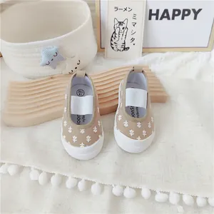 Primer plano de zapatos de lona con flores para niñas con correa elástica.