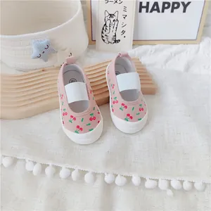 Detalle de zapatos de lona rosa para niñas con un dulce estampado de cerezas y banda elástica.
