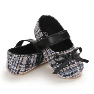 Nahaufnahme von Baby-Laufschuhen aus Tweed mit schwarzer Schleife und weicher Sohle