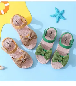 Detailed view of girls' bow sandals in green and tan on a summer beach theme