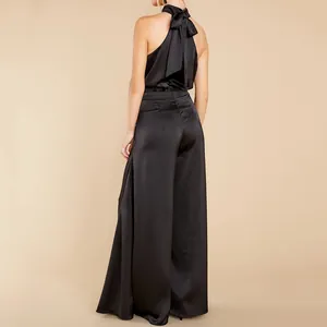 Rückansicht eines eleganten schwarzen Satin-Neckholder-Jumpsuits mit Schleife und weitem Bein.