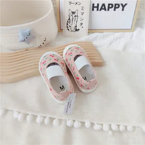 Vista detallada de zapatos de lona rosa para niños con estampado de cerezas y elásticos