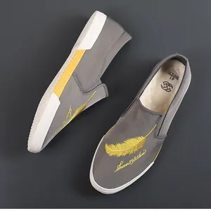 Detailopname van grijze canvas instapschoenen voor heren met gele verenborduur.