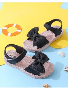 Close-up of girl's black sandals with a large glittery bow on a vibrant background.