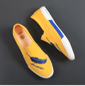 Bovenaanzicht van gele canvas schoenen met blauwe veren borduursel en witte rubberen zool