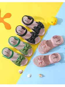 Detail showing colorful kids summer sandals in black green and pink with rhinestone bows.