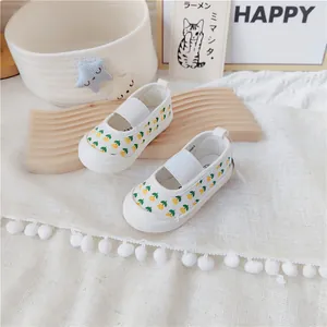 Primer plano de zapatos de lona blancos para bebé con estampado floral amarillo y elástico