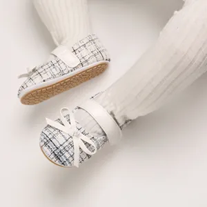 Nahaufnahme von Baby-Prinzessin-Laufschuhen aus blauem Tweed mit weißer Schleife