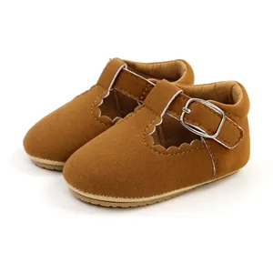 Close-up detail of brown suede baby princess shoes with scalloped edges and buckle strap