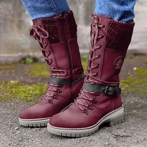 Detail view of burgundy mid-calf boots featuring knit splicing and a buckle strap design.