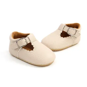Detail view of cream baby walker shoes showing scalloped edges and adjustable metal buckle