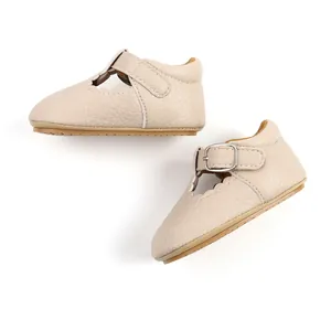 Detail view of beige baby Mary Jane shoes with scalloped edges and T-strap buckle