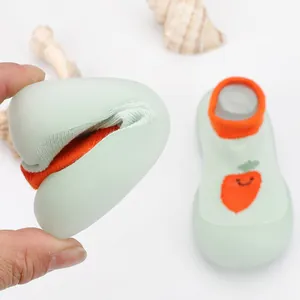 Macro view showing the extreme flexibility of light green baby sock shoes with carrot patterns