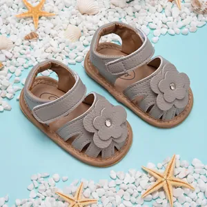Sandales grises pour bébé avec motif floral sur fond de plage et étoiles de mer