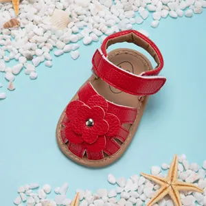 Vue détaillée de la sandale d'été rouge pour bébé avec décoration de fleurs et velcro.