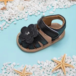 Vue détaillée de la sandale d'été noire pour bébé avec fleur déco et semelle antidérapante