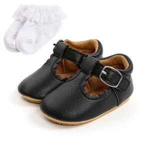 Dettaglio scarpe neonata T-strap nere abbinate a calzini bianchi con pizzo elegante.