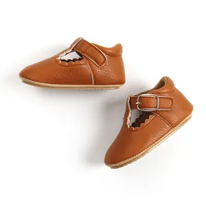 Detail of brown faux leather baby Mary Jane shoes with scalloped edges and metal buckle