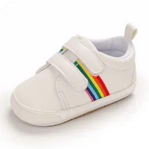 Vue latérale d'une chaussure de bébé blanche avec bande arc-en-ciel colorée