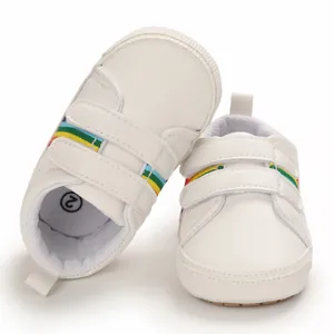 Détail de chaussures de marche blanches pour bébé avec rayures arc-en-ciel et velcro