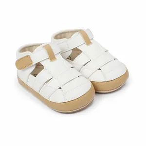 Detailed view of breathable white baby sandals with tan accents and secure velcro strap