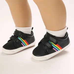 Détail de chaussures de marche bébé noires avec bandes arc-en-ciel vives
