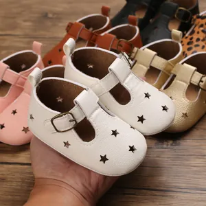 Close-up detail of soft white baby sandals featuring hollow star patterns and metal buckles