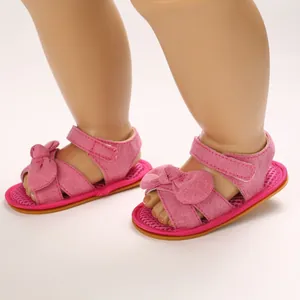 Detalle de sandalias rosas para bebé con lazo y correa ajustable para niños