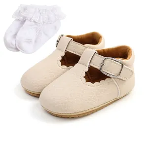 Dettaglio scarpe bebè beige con cinturino a T, bordi smerlati e calzini in pizzo