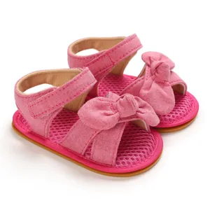 Primer plano de las lindas sandalias para bebé de algodón rosa con lazo y suela de goma