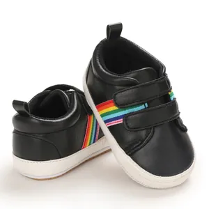 Détail de chaussures de marche noires pour bébé avec rayures arc-en-ciel et semelles souples
