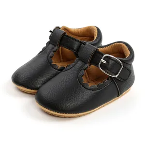 Close-up of black leather baby princess shoes with scalloped edges and T-strap buckle