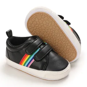Vue détaillée de chaussures de marche bébé noires avec rayures arc-en-ciel et semelles.