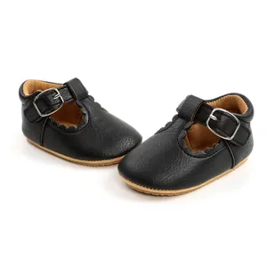 Close-up of elegant black scalloped baby girl T-strap shoes showing sole and buckle detail.