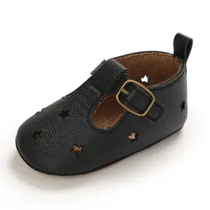 Detail shot of black leather baby walker shoe featuring star cutouts and golden buckle