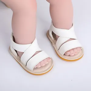 Gros plan de sandales d'été blanches pour bébé avec brides croisées sur pieds