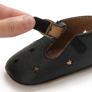 Close-up of black baby walking sandal with star cutouts and adjustable velcro strap.