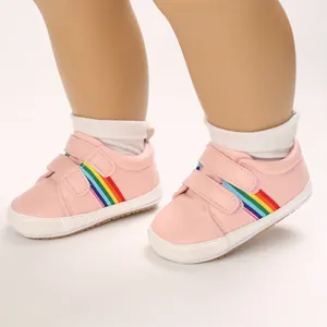 Détail de chaussures bébé roses avec rayures arc-en-ciel et fermeture auto-agrippante