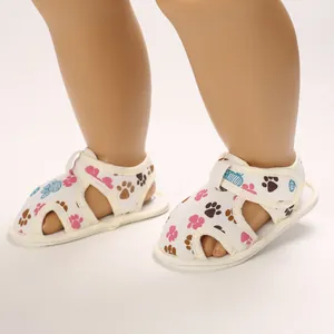 Primer plano de sandalias para bebé con suela blanda, estampados de huellas y velcro