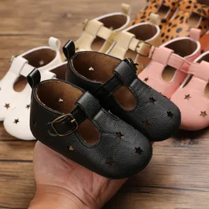 Close-up of black baby pre-walker shoes with star cutouts and gold buckle detail