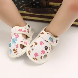 Primer plano de sandalias para bebé con huellas de patas y velcro.