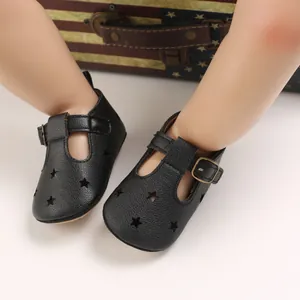Detail of black baby walking shoes with star cutouts and T-strap buckle closure