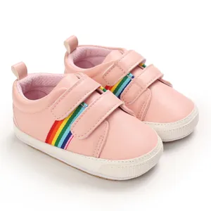 Chaussures de marche roses pour bébé avec rayures arc-en-ciel et semelles souples.