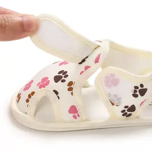 Primer plano del cierre de velcro en las sandalias para bebé con estampado de huellas.