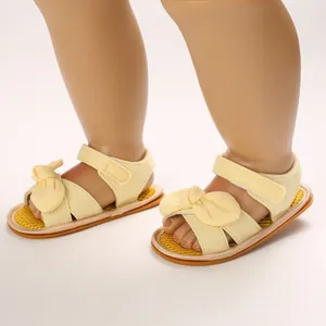 Detalle de sandalias amarillas para bebé con lazo y suela de goma blanda texturizada