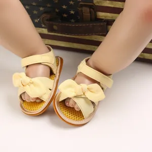 Primer plano de lindas sandalias amarillas de algodón para bebé con lazos en un modelo