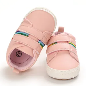 Détail des chaussures bébé roses avec des rayures arc-en-ciel et semelles souples