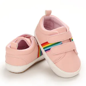 Chaussures de marche roses pour bébés avec rayures arc-en-ciel et semelle souple.