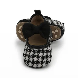 Detailansicht von Baby Mädchen Mary Jane Schuhen mit Hahnentrittmuster und schwarzer Schleife.
