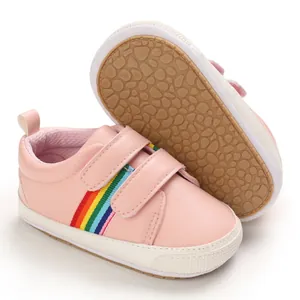 Vue détaillée de baskets roses pour bébé avec rayures arc-en-ciel et semelles en caoutchouc souple
